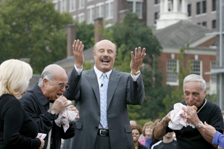 Dr. Phil gets cheesesteak kings Frankie Oliveri (left) of Pat's and Joey Vento (right) of Geno's to try each other's cheesesteaks while taping a show in Philadelphia today. (Charles Fox / Staff Photographer)