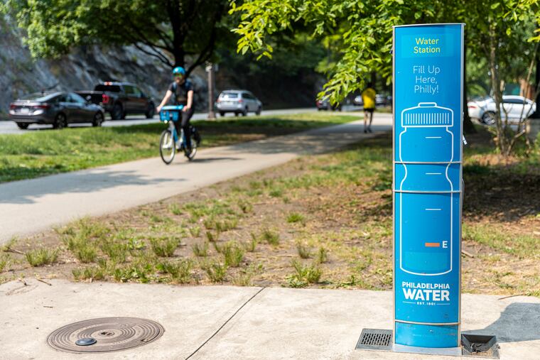 One of the blue water fountains stationed along Kelly Drive as a biker passes by in Philadelphia on Tuesday.