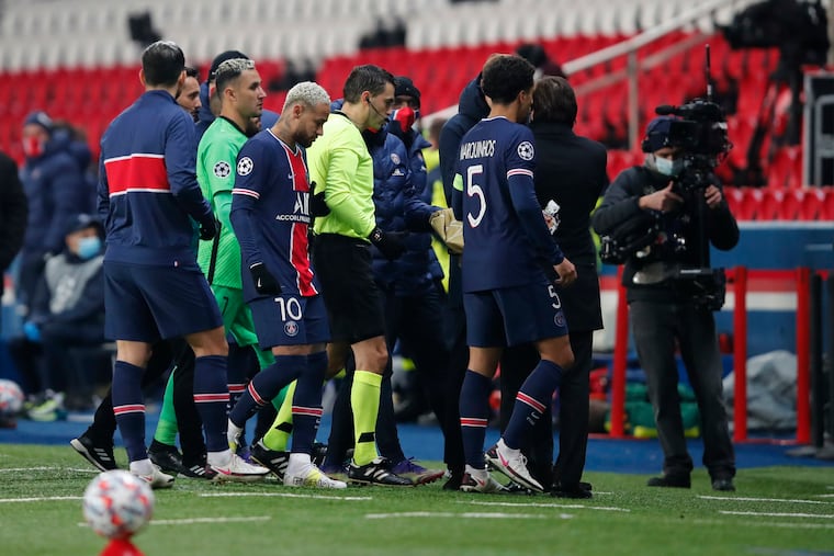 Paris Saint-Germain players and the referee leave the field after the fourth official was accused of making a racist remark toward an Istanbul Baskasehir assistant coach.