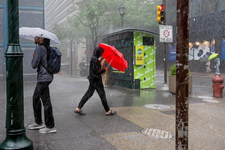 Pedestrians on Chestnut Street outside Liberty Place during heavy rains in July. More showers and thunderstorms are forecast for the weekend.