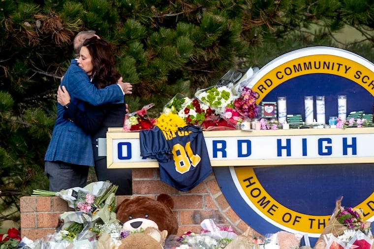 Gov. Gretchen Whitmer embracing Oakland County Executive Dave Coulter as the two left flowers and paid their respects Thursday at Oxford High School, where hundreds have built a memorial outside in honor of the four students killed in Tuesday's school shooting.