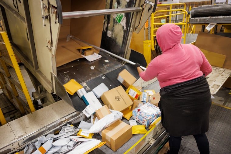 A postal worker at the USPS Philadelphia Processing and Distribution Center uses a machine to sort packages in this December photo.