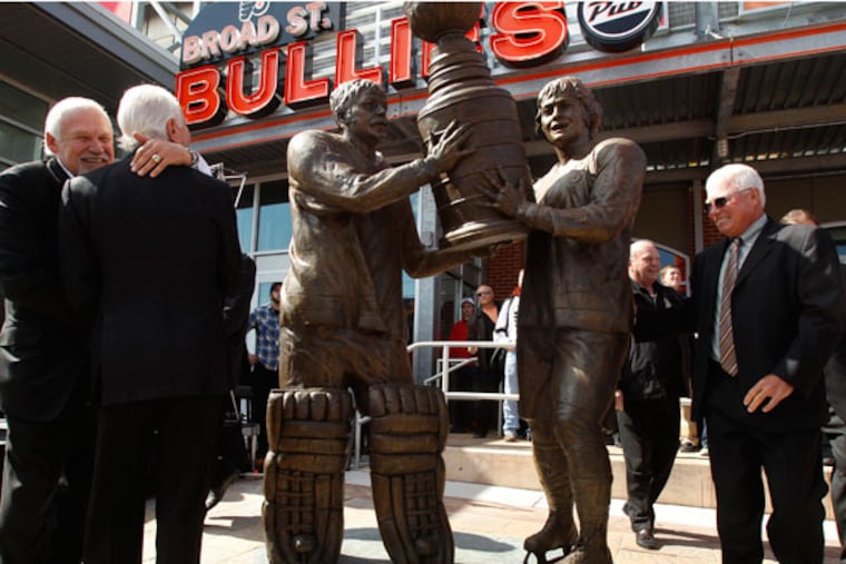 Bernie Parent (left) hugs Ed Snider as Bobby Clarke (right) checks out their statue. (Ron Cortes/Staff Photographer)