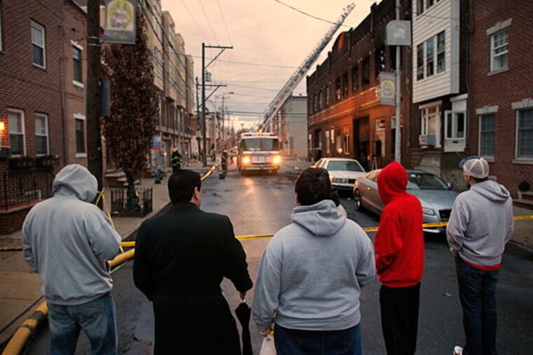 Members of the Fralinger String Band watch as firefighters deal with the aftermath of Monday's blaze at a South Philly warehouse that housed their props and floats. (Alejandro A. Alvarez/Staff)