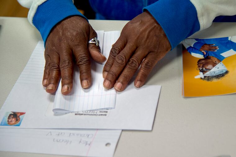 Darlene Harcum folds up a letter to her son during a Family Portrait and Letter Writing Day hosted by photographer Tyreek Dekeyser at the Village of Arts and Humanities.