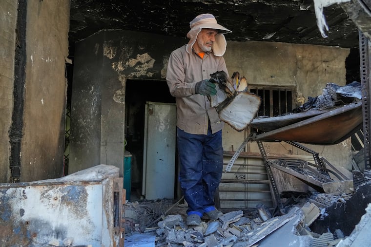 A volunteer flips a burnt book amid the debris of a residential building that, according to the authorities, was damaged on March 4 during the U.S.-Israeli military campaign, in southeastern Tehran, Iran, Tuesday, April 14, 2026.