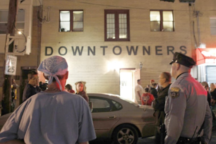A police officer and others watching the prostitution raid Tuesday at the South Philadelphia clubhouse of the Mummers' Downtowners Fancy Brigade. Thirteen people were arrested. (Yong Kim / Staff Photographer)