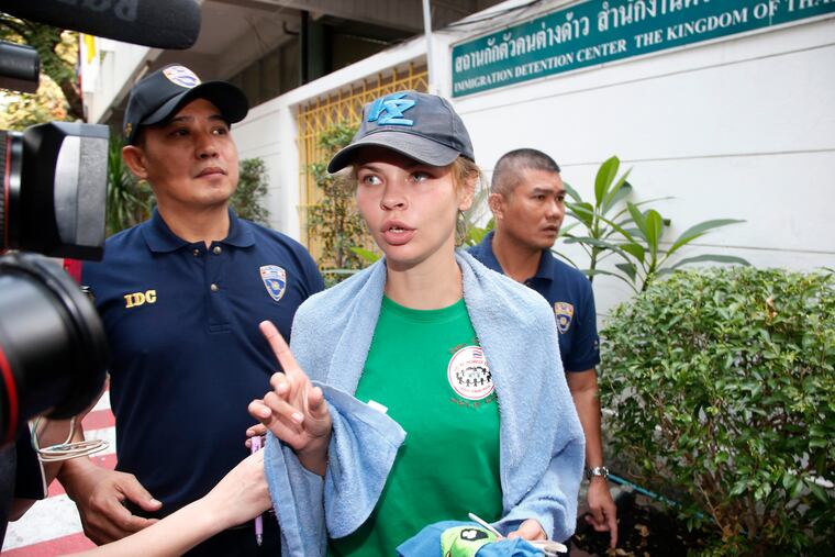 Belarusian model Anastasia Vashukevich talks to journalists as she is escorted from the Immigration Detention Center towards a vehicle to take her to an airport for deportation in Bangkok, Thailand, Thursday, Jan. 17, 2019. Thai officials say they are deporting Vashukevich who claimed last year that she had evidence of Russian involvement in helping elect Donald Trump president. (AP Photo/Sakchai Lalit)