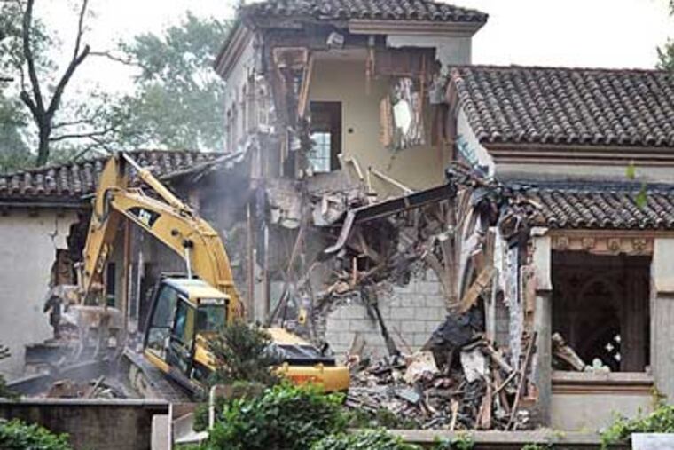 Heavy equipment crunches away at the 80-year-old mansion this morning. (Sharon Gekoski-Kimmel / Staff Photographer)