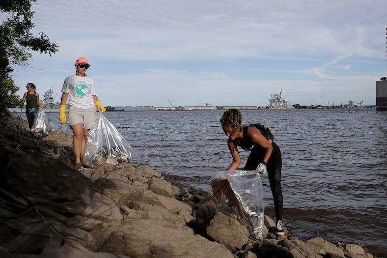 Jana Mars, of right, of Aqua Vida, and Carol Muracco, center, of the Ike Foundation, pick up trash during a Delaware Watershed cleanup in Philadelphia, PA on June 12, 2019. 34 volunteers removed 1248.5 lbs from the area around the Chart House.
