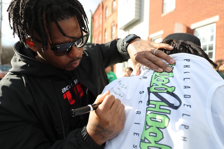 George Morse, of Black Men Running, writes a message on a running jersey at a makeshift memorial for fellow runner and fallen Temple University Police Officer Christopher Fitzgerald near 17th and Montgomery Sunday.