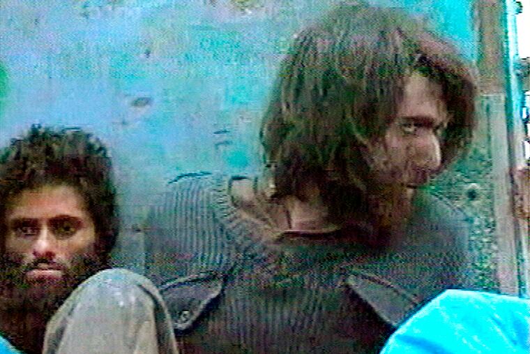 FILE - This file image taken Dec. 1, 2001, from television footage in Mazar-i-Sharif, Afghanistan, shows John Walker Lindh, right, claiming to be an American Taliban volunteer. Lindh, the young Californian who became known as the American Taliban after he was captured by U.S. forces in the invasion of Afghanistan in late 2001, is set to go free Thursday, May 23, 2019, after nearly two decades in prison.