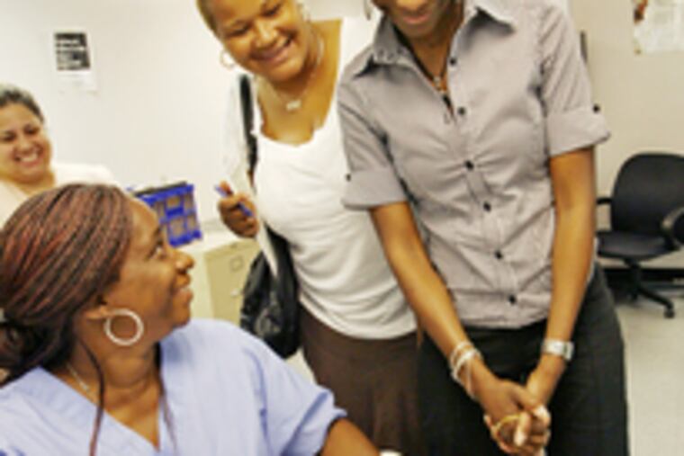 Laptop recipients Vanessa Brown (left) and Kay Miller (in white blouse) beam as Dionne Ellison gives laptop instruction Monday.