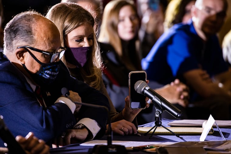 Jenna Ellis, a member of President Donald Trump's legal team, holds up a cell phone to the microphone so Trump can speak during a Pennsylvania Senate Majority Policy Committee public hearing at the Wyndham Gettysburg Hotel to discuss 2020 election issues and irregularities on Wednesday. With her, Rudy Giuliani is continuing his push to overturn election results in the courts.