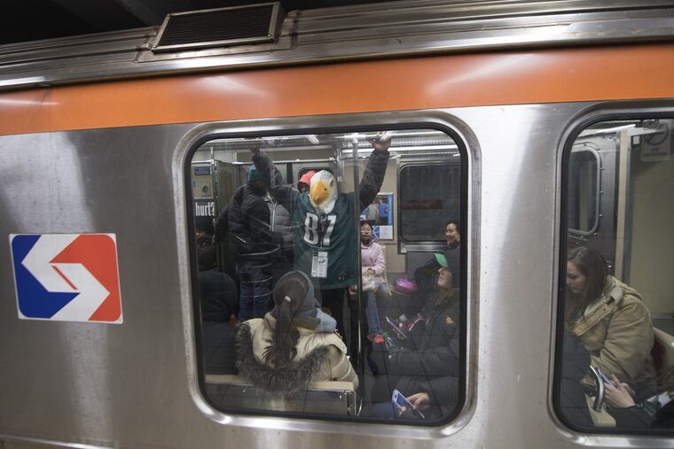 A mask-wearing Eagles fan boards the Broad Street Line at its Race-Vine station after Super Bowl Champions parade Thursday in Philadelphia.