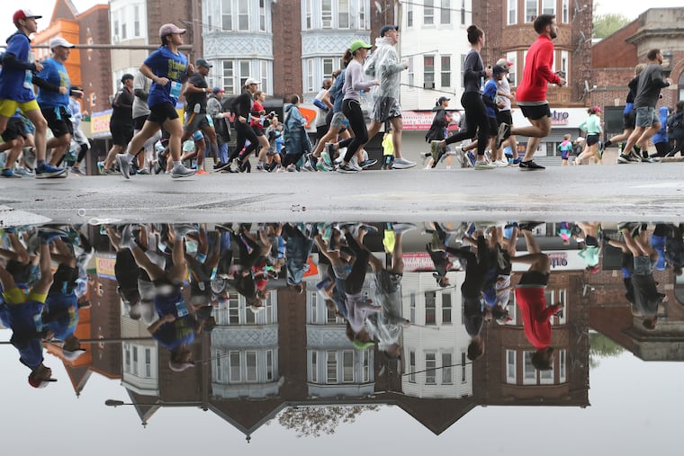Runners are reflected in a puddle at Broad and Windrim Ave. during the 43rd annual Independence Blue Cross Broad Street Run in Philadelphia on Sunday.