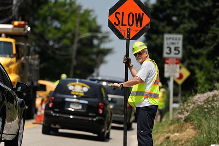 PennDOT worker Mike Bryan directs traffic along Crooked Lane in Bridgeport as a road crew repaired asphalt. ( RON TARVER / Staff Photographer )
