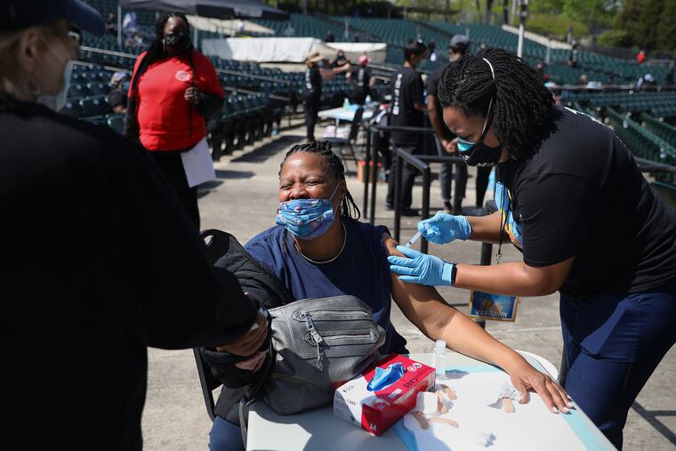 Carol Green (center) of Strawberry Mansion holds the hand of nurse Pat D'Antonio (left) as nurse Cydni Walker gives her a vaccine during the Philly Vax Jawn COVID-19 clinic earlier this month.