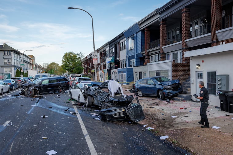 A Philadelphia Police officer gathers evidence at a fatal crash scene along Walnut Street near 48th Street on Friday.