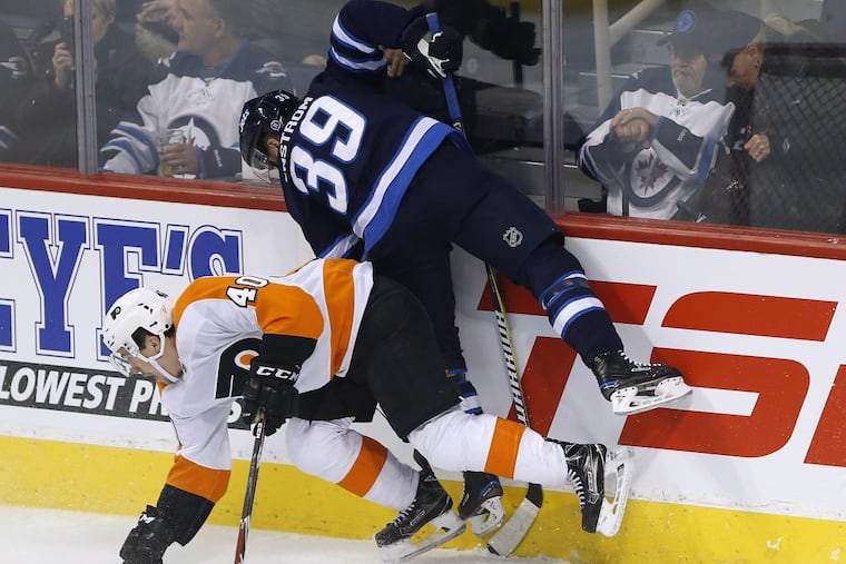 The Flyers Jordan Weal (40) and Winnipeg’s Toby Enstrom collide behind the Jets net during first-period action.