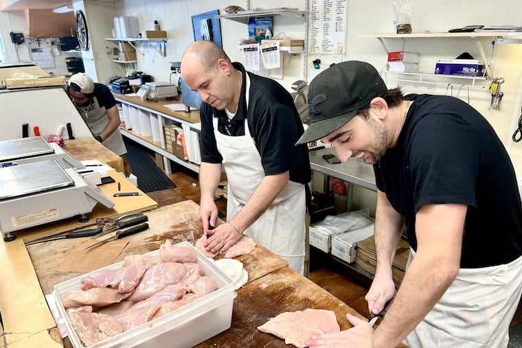 New owner Rob Passio (center) and worker Vince Lombardi, grandson of the founder, slice chicken cutlets at Lombardi's Prime Meats, 1801 Packer Ave.