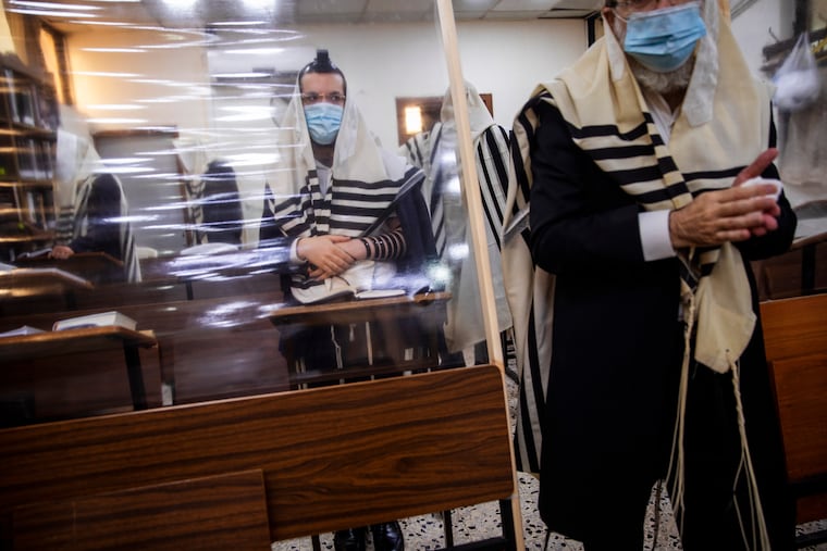 Ultra-Orthodox Jews, wearing face masks during a morning prayer in a synagogue divided by plastic partitions, follow new government measures to help stop the spread of the coronavirus, in Bnei Brak, Israel, on Friday.