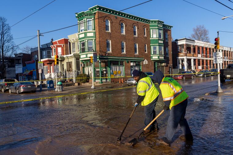 Philadelphia Water Department workers looking for something under the flowing water underneath 56th Street at Chester in Southwest Philadelphia. Philadelphia Water Department, Fire and Police were at water main break on 56th Street between Springfield and Chester in southwest Philadelphia on Wednesday morning February 9, 2022.