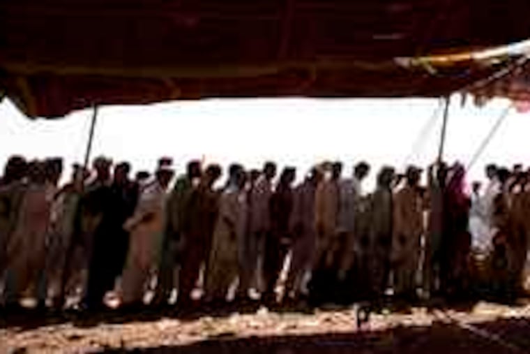 Displaced men waited yesterday at a refugee camp near Peshawar for rugs and buckets. In northwest Pakistan, troops faced a tough fight for the city of Mingora.
