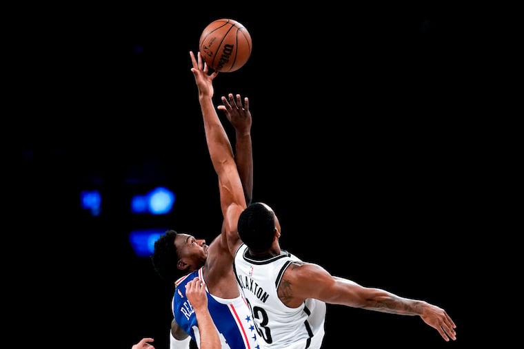 Sixers forward Paul Reed (left) and Brooklyn Nets forward Nic Claxton battle for the ball at tip-off during the preseason game Monday.