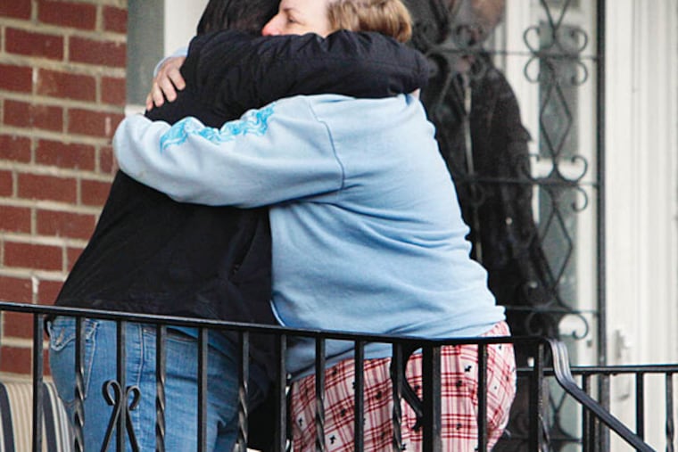 Two neighbors hug as police gather on the 300 block of Stevens Street after a woman and her adult son were found shot to death. (Joseph Kaczmarek)