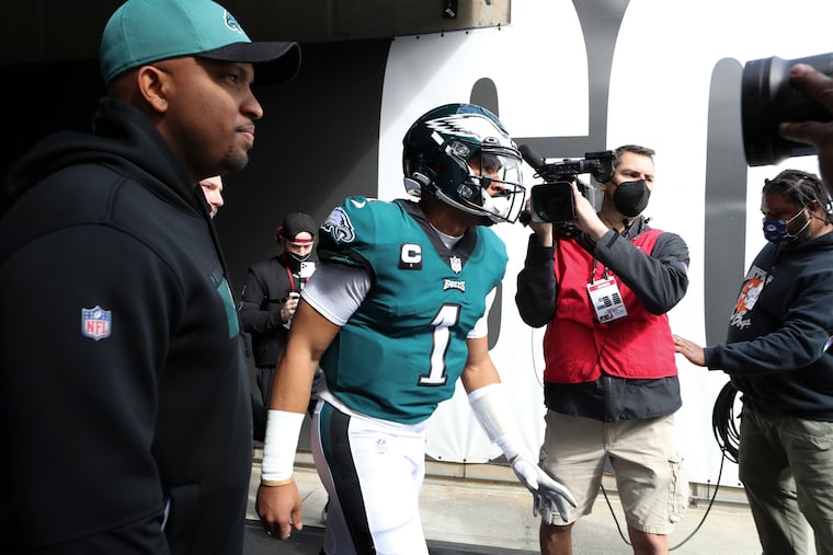Eagles quarterback Jalen Hurts and assistant coach Brian Johnson get ready to take to the field before the playoff loss to the Tampa Bay Buccaneers on Jan. 16, 2022.