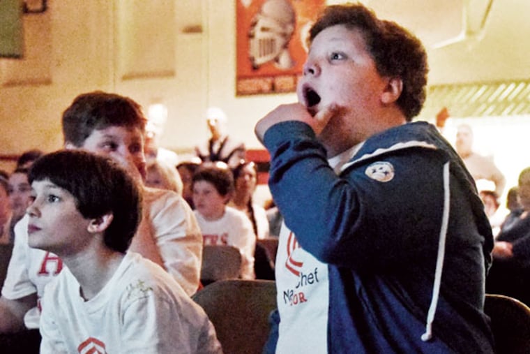 Andrew Zappley, right, reacts to something chef Gordon Ramsay said as he, schoolmate Anthony Tratas, left, and a gym full of friends watch a previous broadcast of "MasterChef Junior." (Curt Hudson/For the Inquirer)