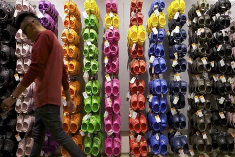 FILE - In this Friday, April 9, 2010, file photo, Summett Kumar, a Crocs ambassador, works at a Crocs store inside the Beverly Center shopping mall in Los Angeles. Crocs shoes is getting a $200 million bailout from private equity fund Blackstone and CEO John McCarvel is retiring, according to reports Monday, Dec. 30, 2013. (AP Photo/Damian Dovarganes, File)