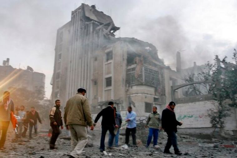 Palestinians gather near the ruins of a Gaza building hit by an Israeli missile.