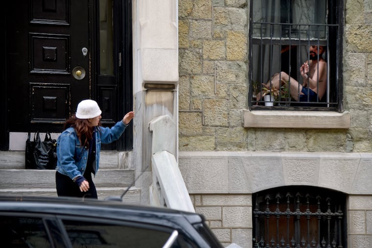 Tyler Borchardt (left) waves while maintaining social distance after dropping off some provisions for Justin Donahue (right) who is isolating at home. Visitors from certain southern states must self-quarantine for 14 days before visiting New Jersey, New York, and Connecticut, the governors announced Wednesday.