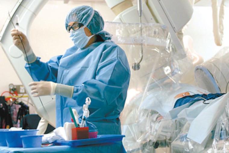Andrea Russo, an electrophysiologist at Cooper University Hospital in Camden, prepares a catheter for ablation. In ablation, sections of heart muscle that are sending errant electrical signals are isolated by scarring tissue with heat or cold. (Tom Gralish / Staff photographer)