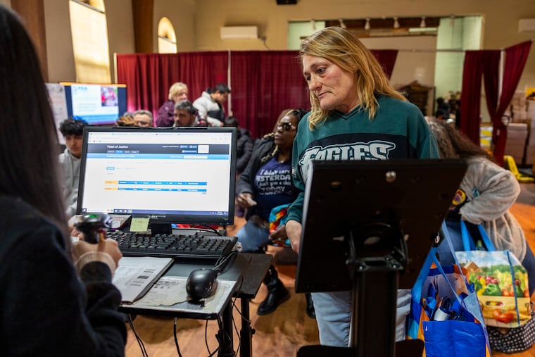 Lisa Mellon, 59, of Bridesburg, Pa, is called up for her number and checks in before picking out her food at Feast of Justice food bank at St. John’s Lutheran Church on Tuesday, Nov. 11, 2025. The Trump administration is again threatening SNAP benefits after a disruption caused by the shutdown last month.