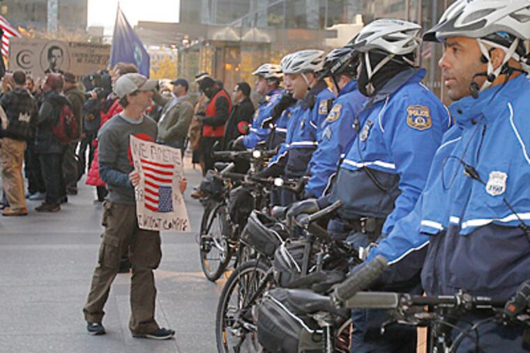Bike police officers at the Comcast Center watched demonstrators as they protested the company’s tax breaks and the pay of Comcast’s CEO. (Akira Suwa / Staff Photographer)