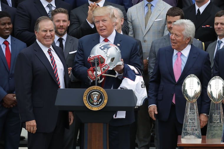 New England Patriots head coach Bill Belichick (left) and team owner Robert Kraft (right) present a football helmet to then-President Donald Trump during a celebration of the team's Super Bowl victory on the South Lawn of the White House in 2017.