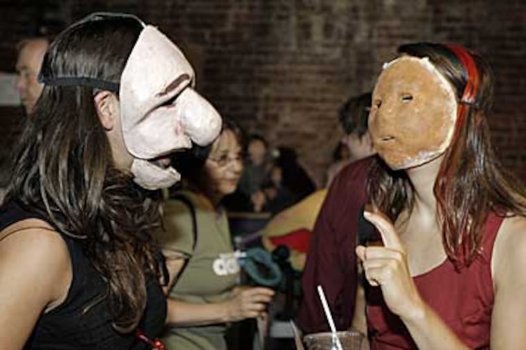 Tracy Broyles (left) and Leslie Rogers try on masks at the Mum Puppettheatre, which sold off its remaining props and puppets left over from 23 years of performances in Philadelphia. (AKIRA SUWA / Inquirer)