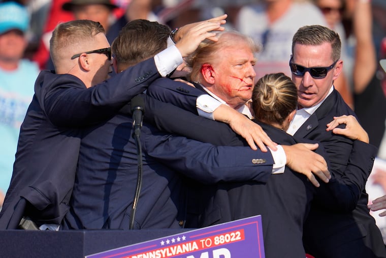 Republican presidential candidate former President Donald Trump is surrounded by U.S. Secret Service agents as he is helped off the stage following an assassination attempt a campaign rally in Butler, Pa., on Saturday, July 13, 2024.