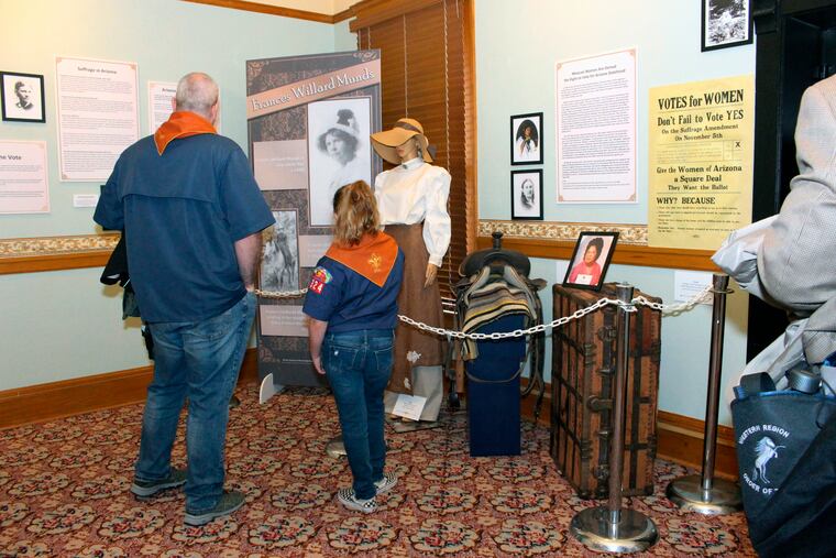 Visitors to the Arizona Capitol Museum in Phoenix look at a display honoring the state’s early suffrage movement.