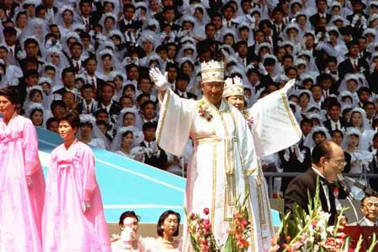 Unification Church founder Sun Myung Moon and his wife, Hak Ja Han, waving to thousands of believers during a 1990s mass wedding ceremony at Seoul's Olympic Stadium.