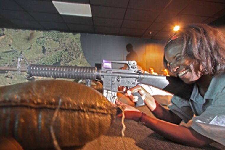 Central High School guidance counselor Lisa Sancho aims an M-4 carbine on the computer-simulated firing range. (DAVID M WARREN / Staff Photographer)