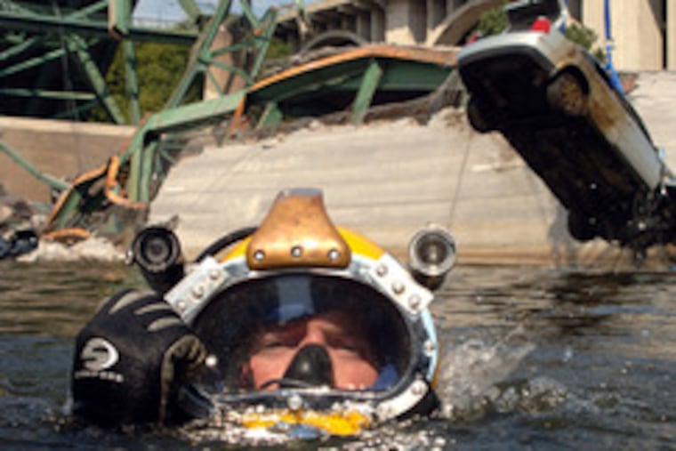 A diver surfaces after a salvage effort in the Mississippi River in Minneapolis. Nearby a vehicle his team rigged is pulled from the water. The death count in the bridge collapse rose to seven yesterday with two more bodies found. Story, A3.