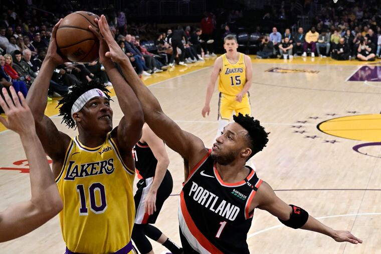 Los Angeles Lakers forward Jemerrio Jones, left, shoots as Portland Trail Blazers guard Evan Turner defends.