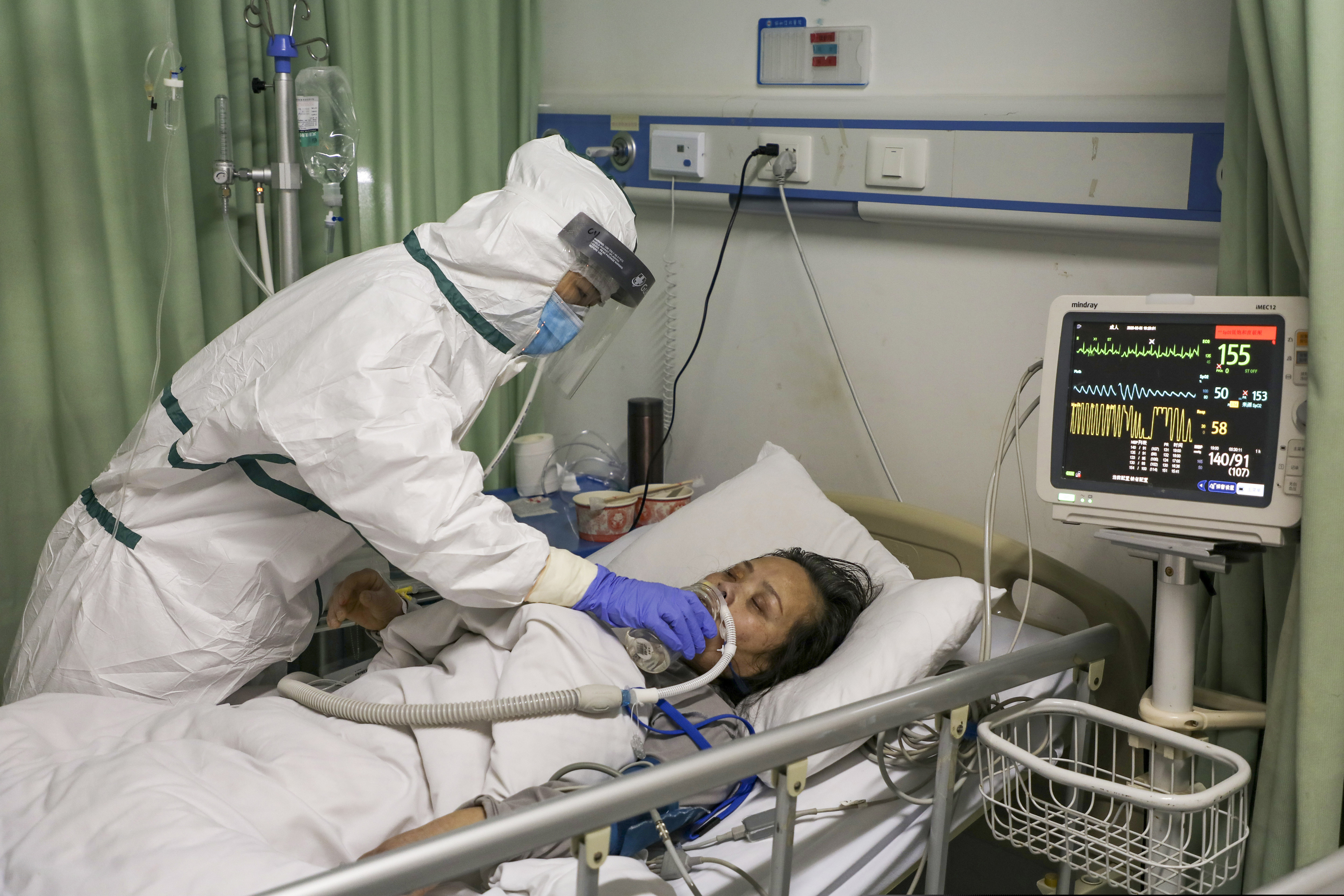 In this Thursday, Feb. 6, 2020, photo, a nurse feeds water to a patient in the isolation ward for 2019-nCoV patients at a hospital in Wuhan in central China's Hubei province. The number of confirmed cases of the new virus has risen again in China Saturday, Feb. 8, 2020, as the ruling Communist Party faced anger and recriminations from the public over the death of a doctor who was threatened by police after trying to sound the alarm about the disease over a month ago.
