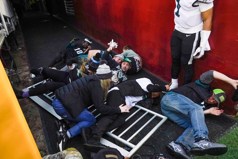 Fans lay on the ground after falling onto Philadelphia Eagles quarterback Jalen Hurts (1) as a railing collapsed following the end of an NFL football game, Sunday, Jan. 2, 2022, in Landover, Md. Philadelphia won 20-16.