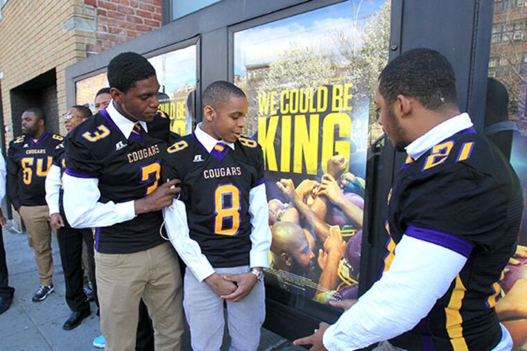 (Left to right) D.J. Brinkley, Emmanuel Clark, and Joseph Walker, members of the Martin Luther King High School football team, check out movie posters outside of Sunshine Cinema in lower Manhattan. The premiere of "We Could Be King " was held during the Tribeca Film Festival on Wed, April 23, 2014. ( CHARLES FOX / Staff Photographer )