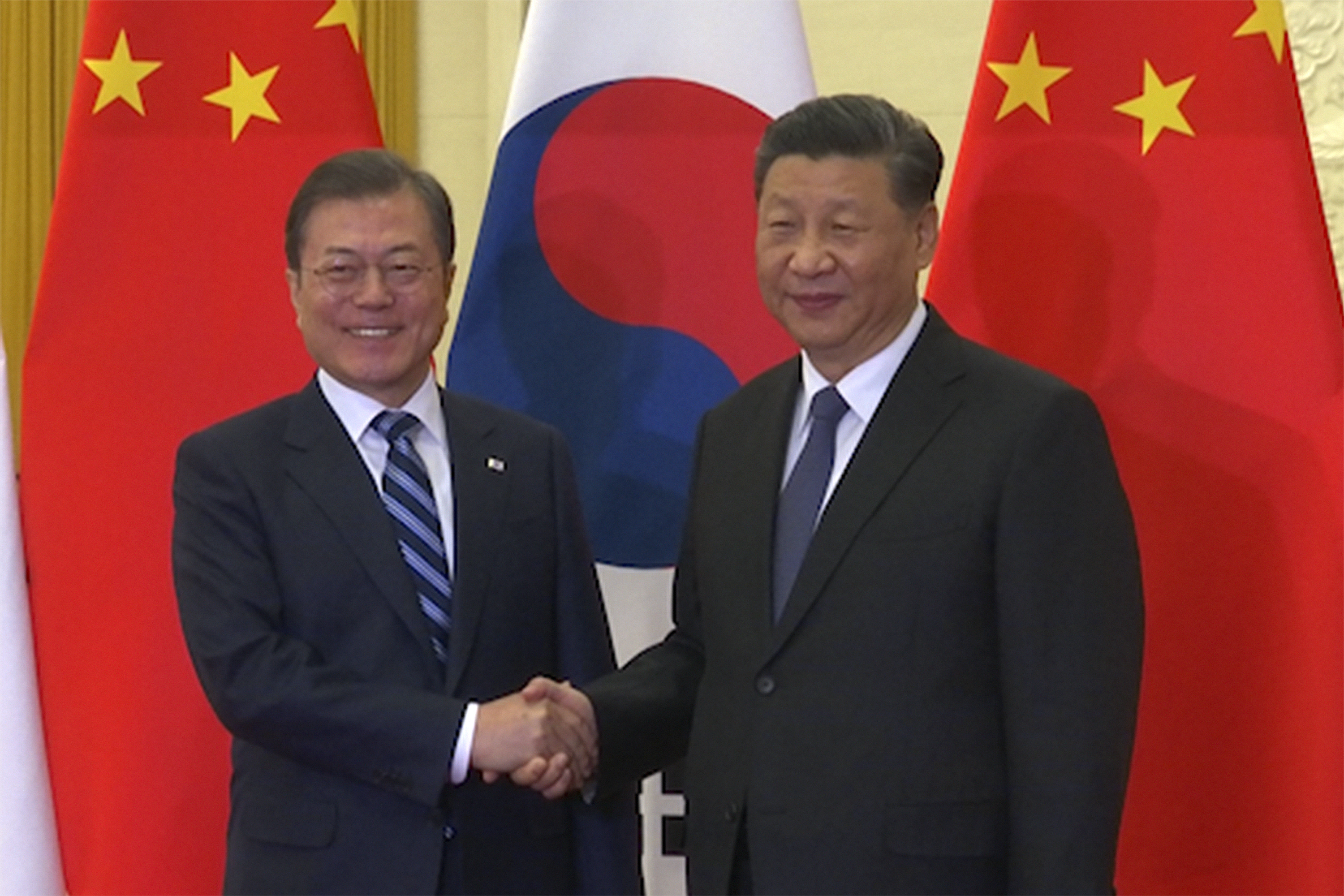 In this image from video, South Korean President Moon Jae-in, left, shakes hands with his Chinese counterpart Xi Jinping as they pose for photographers ahead of their meeting at the Great Hall of the People in Beijing, Monday, Dec. 23, 2019. The leaders of China, Japan and South Korea are holding a trilateral summit in China this week amid feuds over trade, military maneuverings and historical animosities.